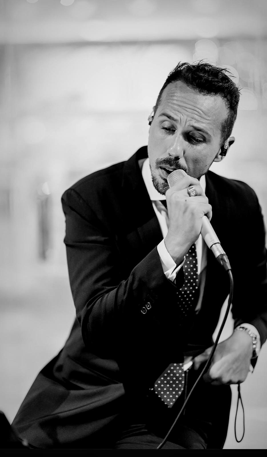 José Blaya interpretando una canción con traje y micrófono
